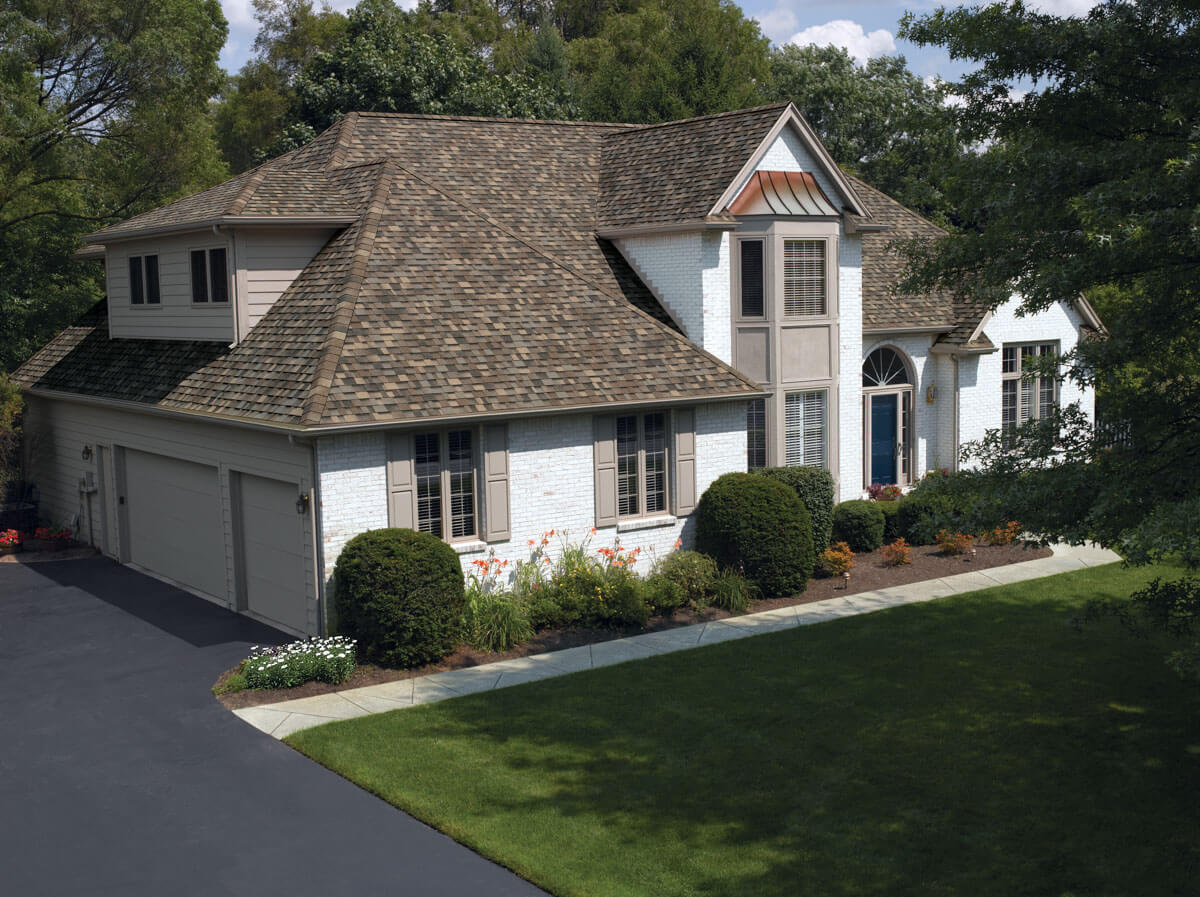 White brick home with a multi-level asphalt shingle roof replacement in Royersford, PA using Owens Corning Sand Dune.